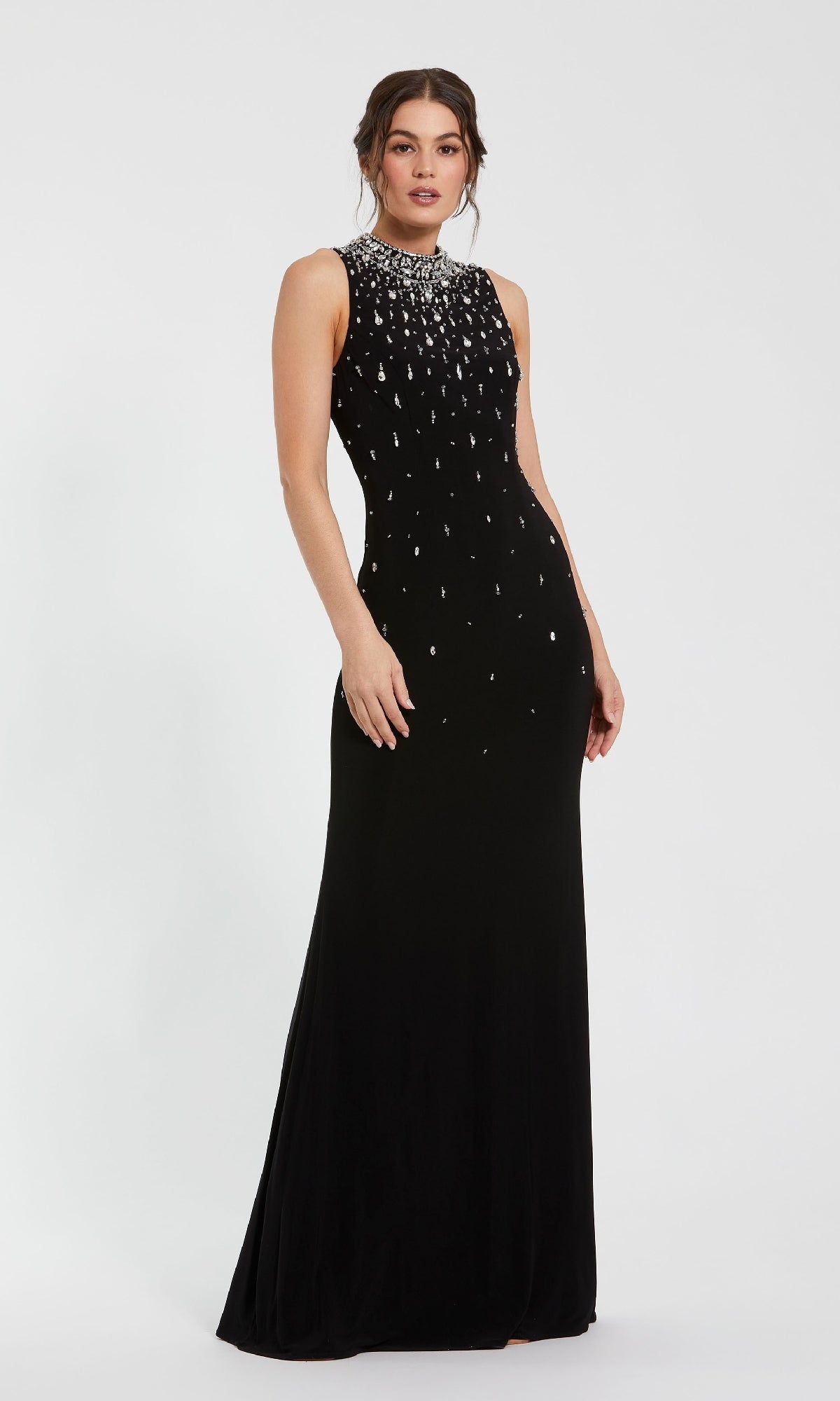A woman models the Mac Duggal 2260 high-neck, sleeveless black formal gown with beaded accents and white jeweled bodice, floor-length, standing against a plain white background.
